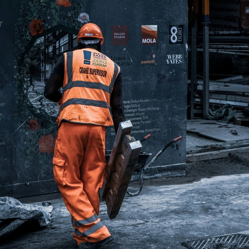 Worker wearing high-visibility workwear and carrying tools