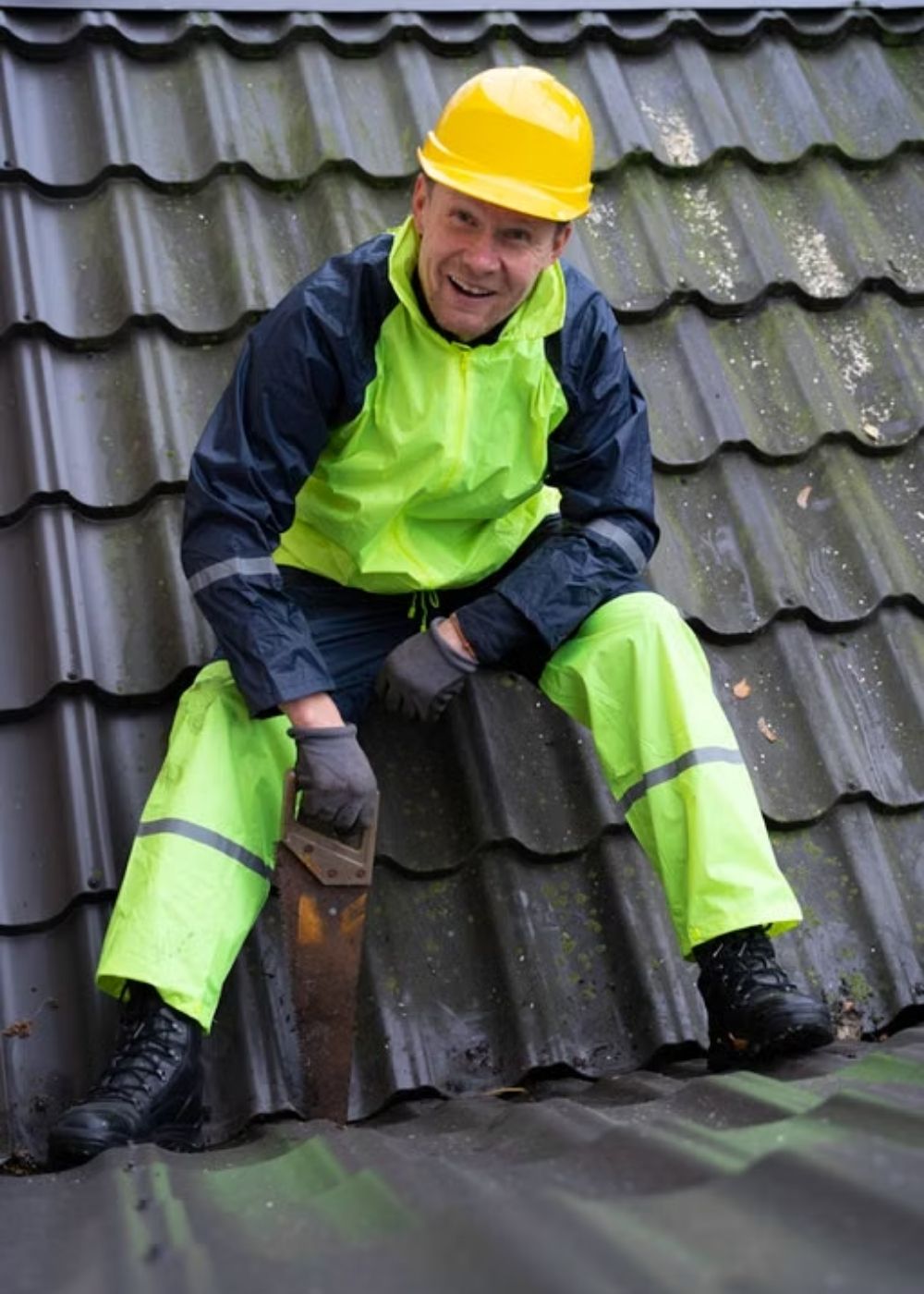 Worker wearing high visibility green workwear and a safety helmet near a building site